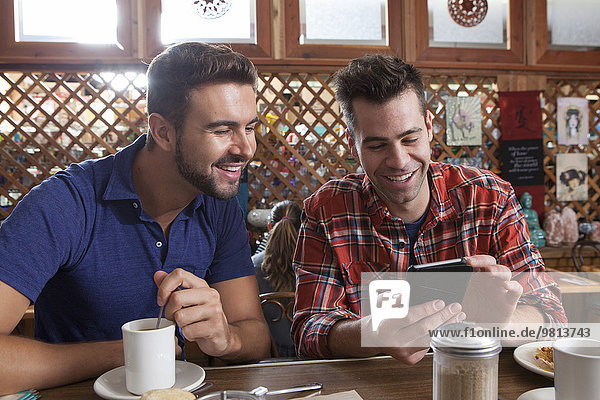 Two male friends looking at smartphone at restaurant bar