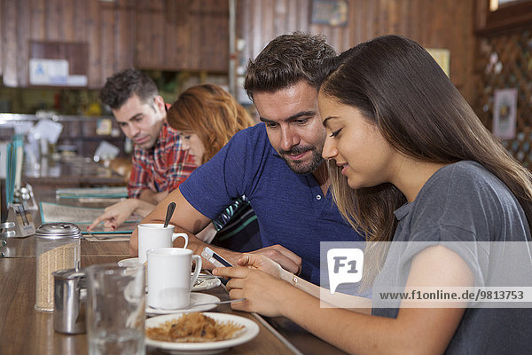 Paar schaut auf Smartphone an der Restaurantbar