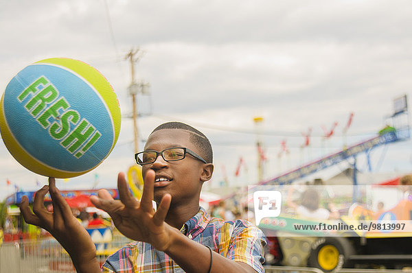 Teenager-Junge spinnt Basketball am Finger im Vergnügungspark
