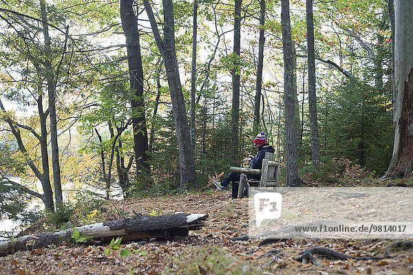 Male hiker sitting on seat in forest  Rangeley  Maine  USA