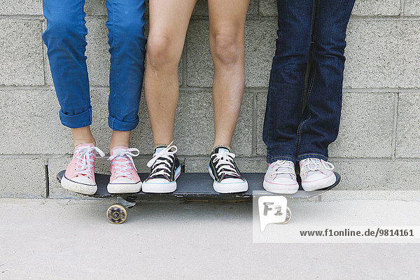 Three girls standing on skateboard  low section