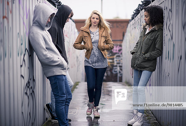 Teenagers standing against wall with graffiti