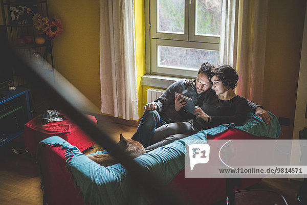 Paar sitzt auf dem Sofa und schaut auf das digitale Tablett.