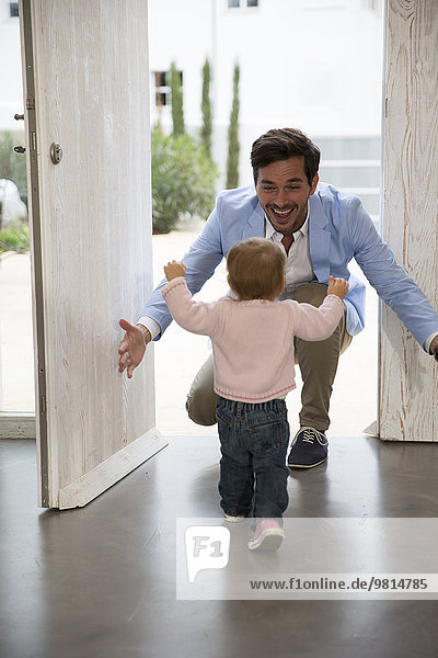 Female toddler running to fathers arms at front door