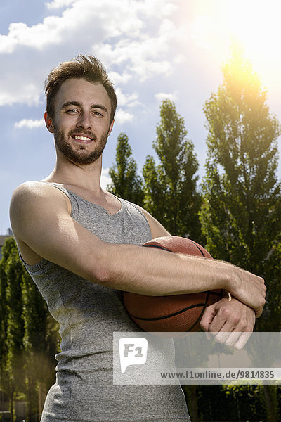 Portrait of young male basketball player holding ball