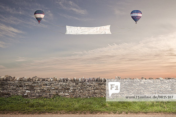 Banner zwischen zwei Heißluftballons über einer Cotswold-Steinwand