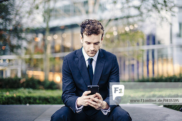 Geschäftsmann beim Lesen von Smartphone-Texten vor dem Büro