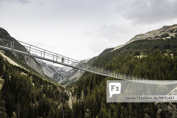 Flachwinkelansicht einer jungen Wanderin über die Fußgängerbrücke  Holzgau  Tirol  Österreich