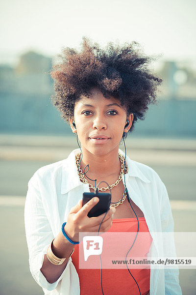 Portrait einer jungen Frau beim Hören von Smartphone-Musik