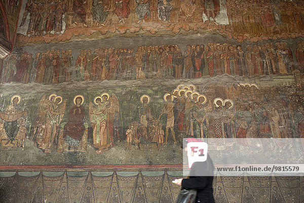 Frau vor der Wand in einer orthodoxen Kirche mit romanischen Fresken  Bukarest  Rumänien