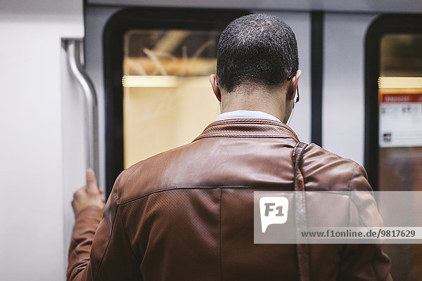 Back view of man on the subway train