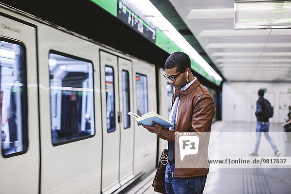 Spain  Barcelona  businessman standing at underground station platform reading book