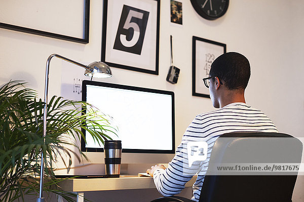 Young creative man working at computer in his home office