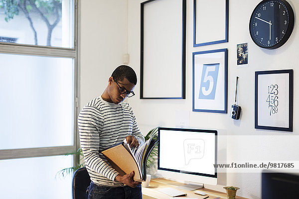 Junger kreativer Mann mit Akten in seinem Home-Office