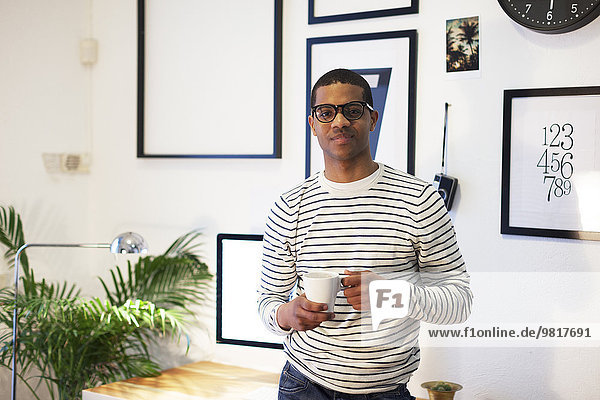 Junger kreativer Mann bei einer Kaffeepause in seinem Home-Office