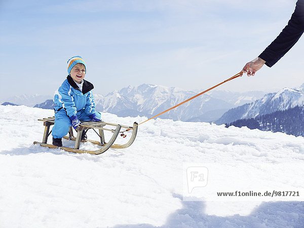 Deutschland  Tegernsee  Wallberg  lächelnder kleiner Junge auf Schlitten sitzend