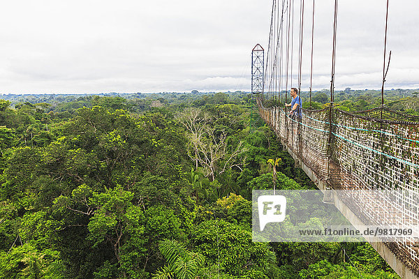 Ecuador,  Amazonasgebiet,  Tourist auf Hängebrücke über Regenwald