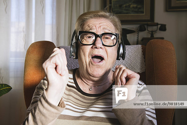 Portrait einer glücklichen älteren Dame  die Musik mit Kopfhörern hört.