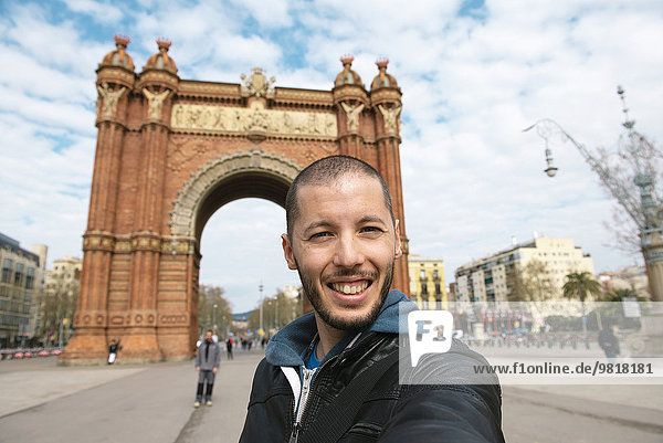 Spanien  Barcelona  glücklicher Mann  der einen Selfie vor dem Trymphalbogen nimmt.