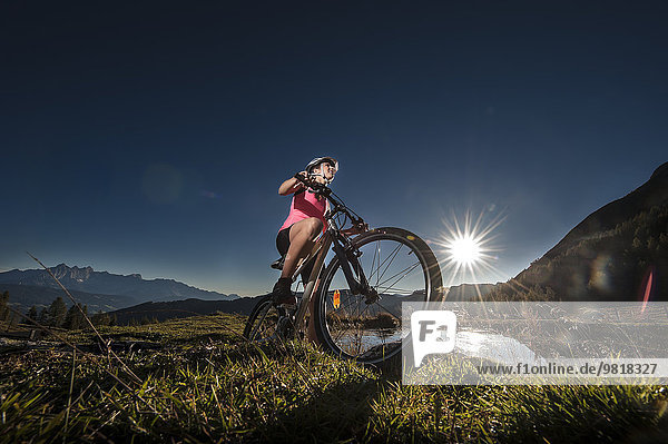 Austria  Altenmarkt-Zauchensee  young woman riding mountain bike at sunrise