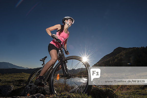 Österreich  Altenmarkt-Zauchensee  junge Frau auf dem Mountainbike bei Sonnenaufgang