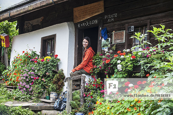 Österreich  Altenmarkt-Zauchensee  junge Wanderin beim Ausruhen vor der Almhütte
