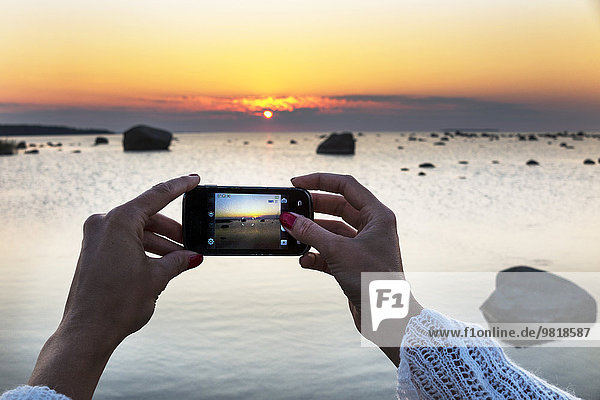 Estland  Kaesmu  Frauenhände fotografieren Sonnenuntergang mit Smartphone