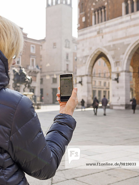 Italy  Piacenza  female tourist with smartphone at Piazza Cavalli