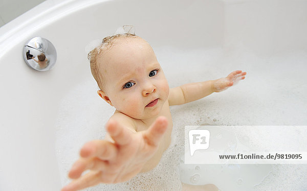 Baby girl in a bathtub with outstretched arm