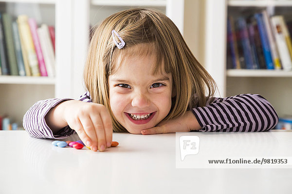 Smiling little girl playing with chocolate buttons