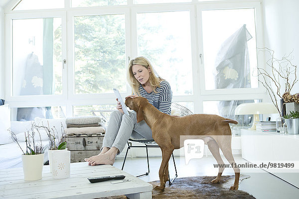 Frau mit Hund und digitalem Tablett zu Hause