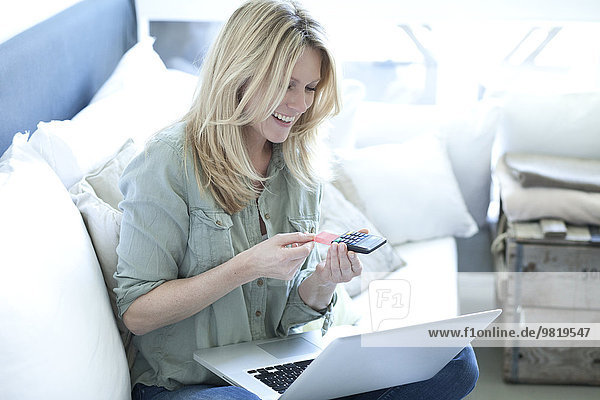 Lächelnde blonde Frau mit Laptop über Online-Banking
