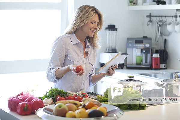 Woman with digital tablet cooking in kitchen