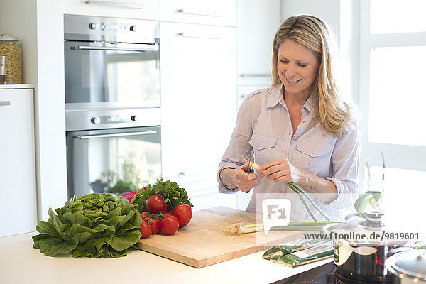 Lächelnde Frau schneidet Gemüse in der Küche