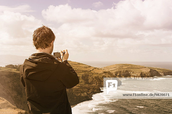Portugal  Azores  man taking picture of coastal landscape