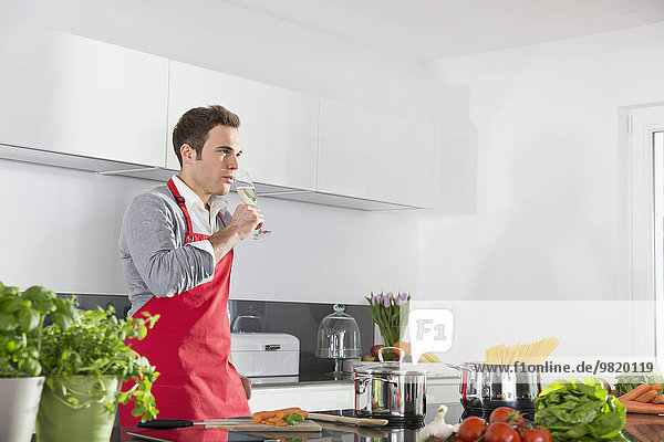 Man relaxing with glass of sparkling wine in kitchen