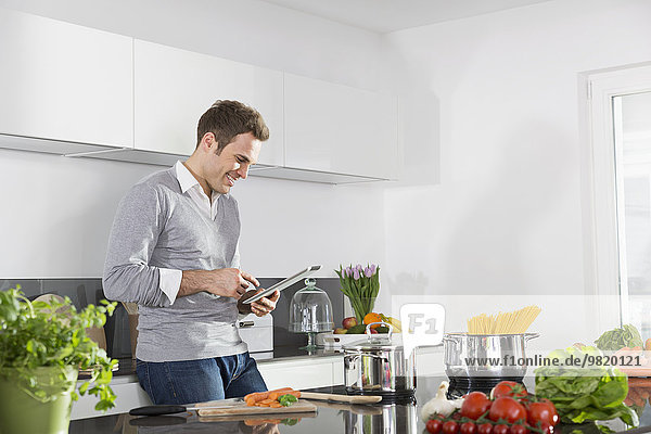 Smiling man using digital tablet in the kitchen