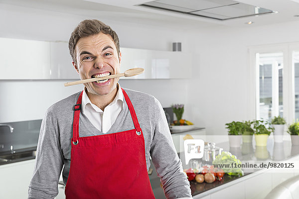 Portrait of man with cooking spoon between his teeth
