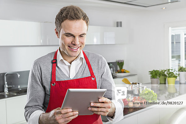 Smiling man looking at digital tablet in the kitchen
