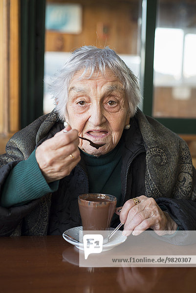 Porträt der Seniorin beim Kakao trinken am Winternachmittag