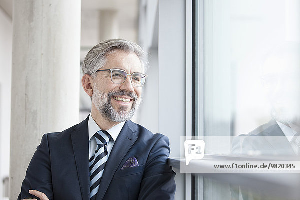Zuversichtlicher Geschäftsmann schaut aus dem Fenster