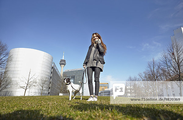 Germany  Dusseldorf  Young woman walking her dog