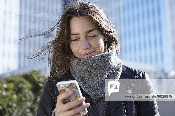 Germany  Dusseldorf  Young woman holding smart phone