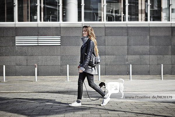 Germany  Dusseldorf  Young woman walking her dog