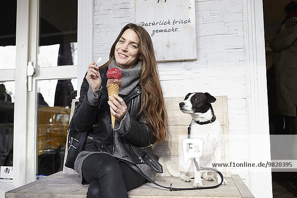 Germany  Dusseldorf  Young woman with dog eating icecream