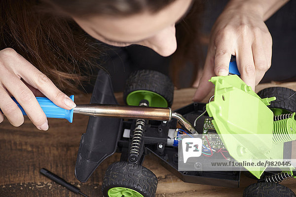 Young woman repairing toy car