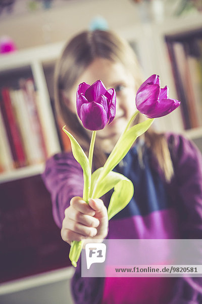 Kleines Mädchen mit zwei violetten Tulpen