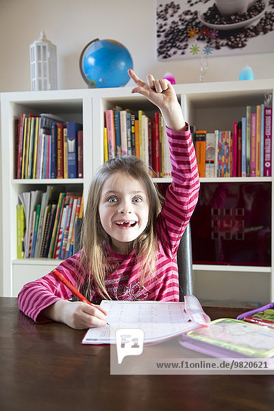 Girl doing homework raising her arm