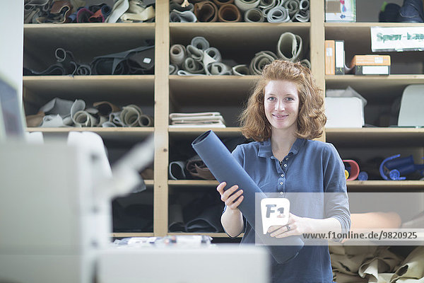 Porträt einer selbstbewussten jungen Frau in der Werkstatt mit Lederrolle