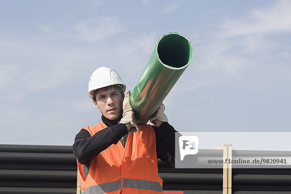 Construction worker carrying pipe on his shoulder
